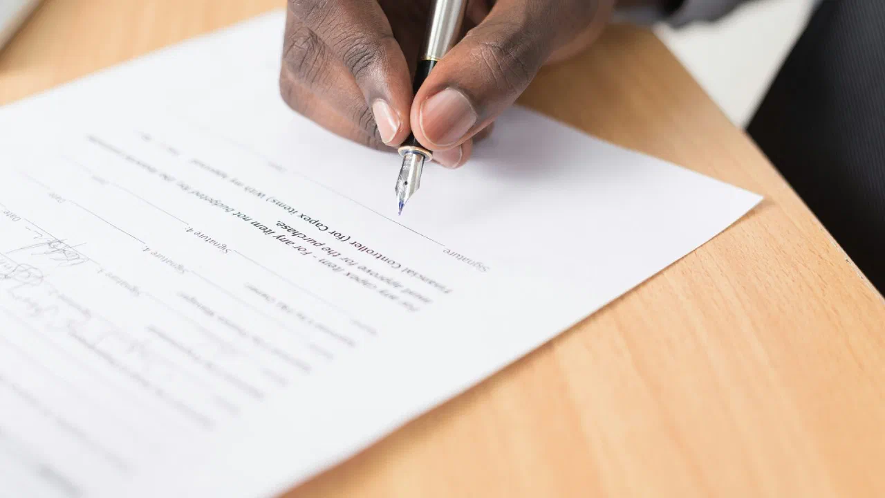 a person writing on a sheet of white paper with a pen