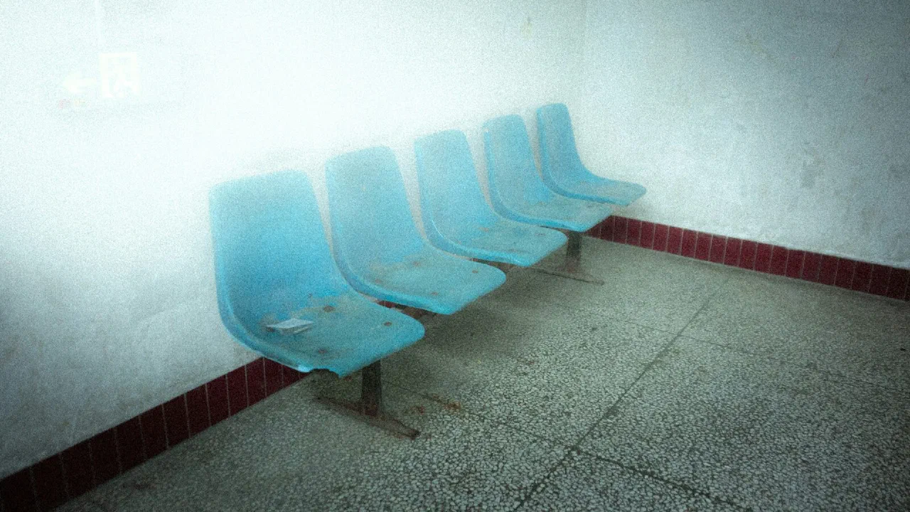 a row of empty blue plastic chairs in a waiting room