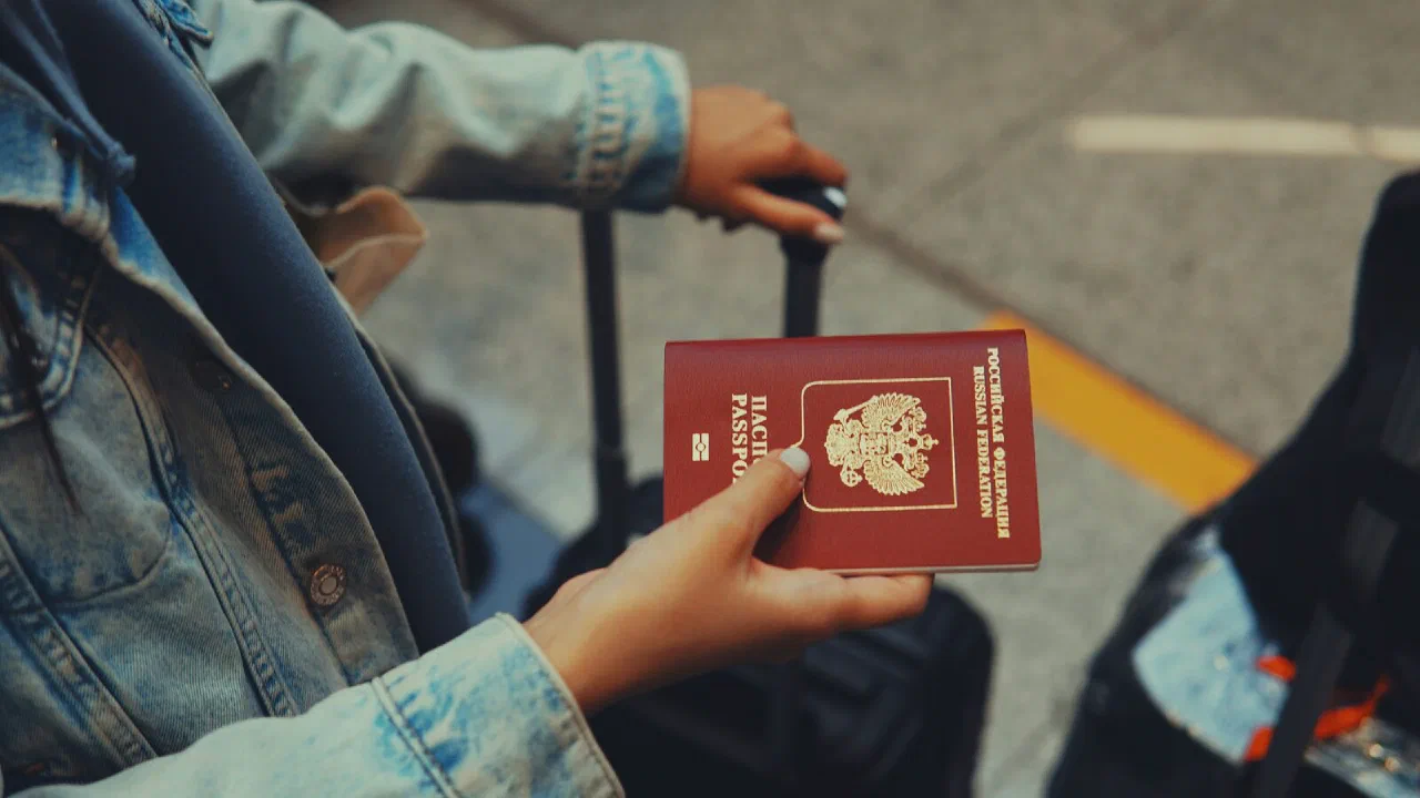 a hand holding a closed red passport
