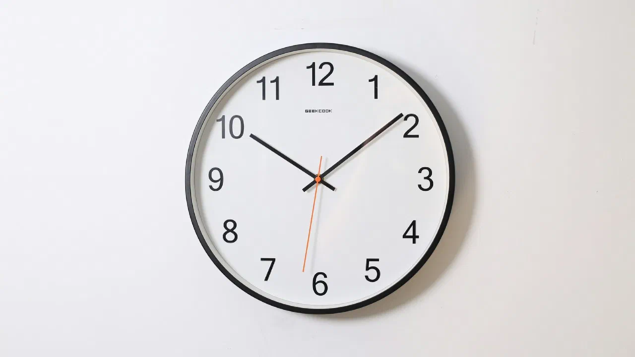 a round analog wall clock on a plain white wall