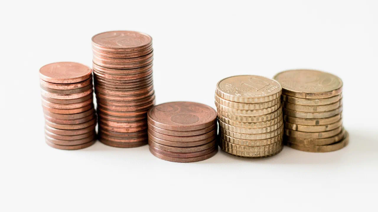 stacks of gold-coloured coins of different heights on a white surface